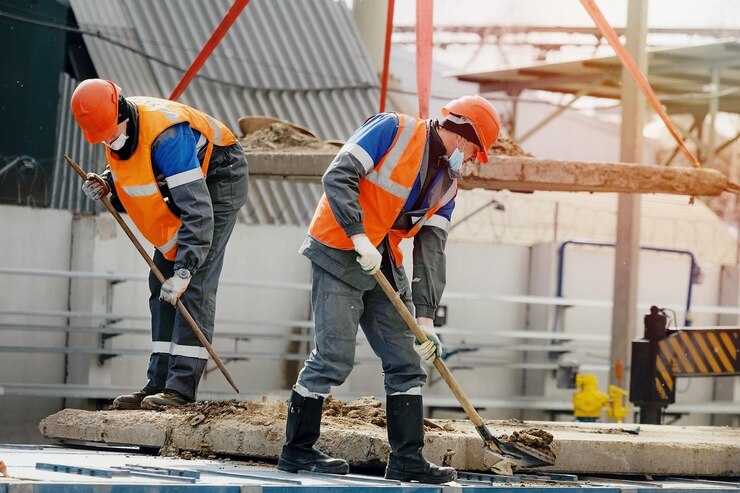 two-workers-hard-hats-work-clothes-medical-mask-work-with-shovels-construction-site-hard-physical-labor_230115-2280